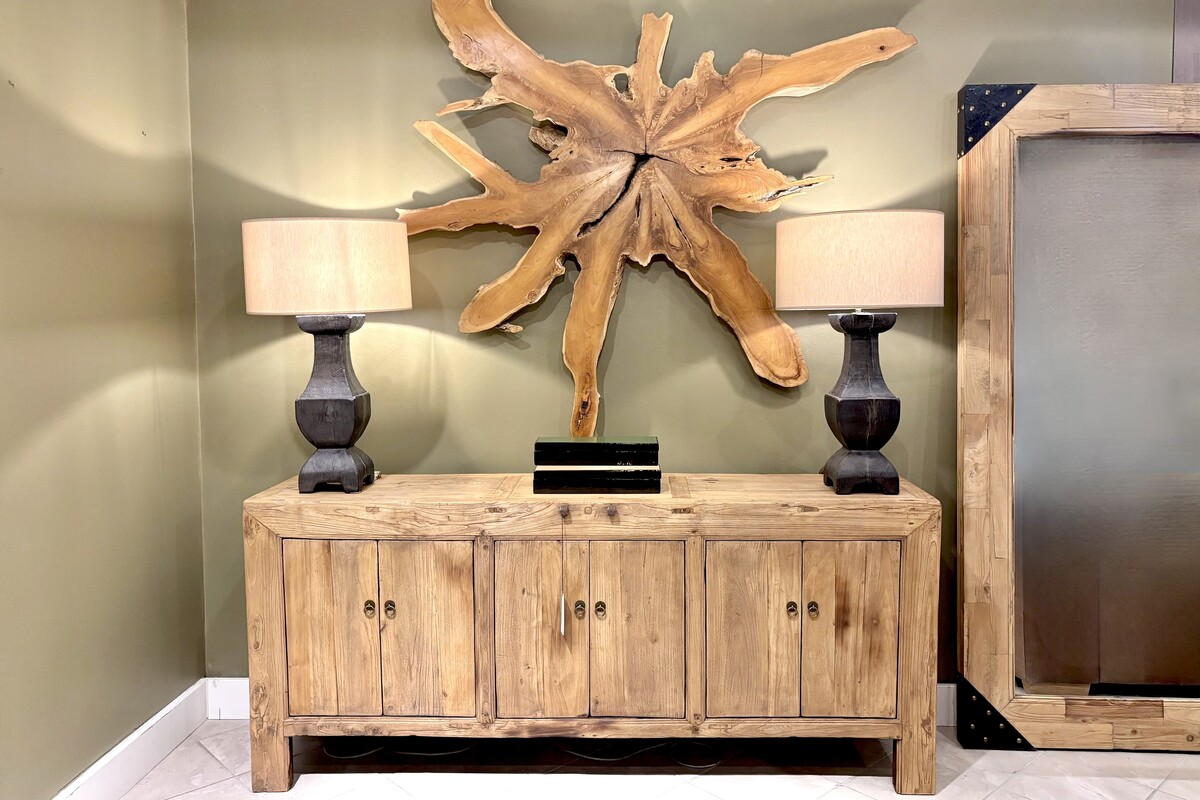 Naturalna komoda do salonu. Długa drewniana komoda. Komoda w stylu boho. Komoda w stylu japandi. Oliwkowa ściana, dekoracja korzeń. Oryginalne duże lustro w drewnianej ramie.