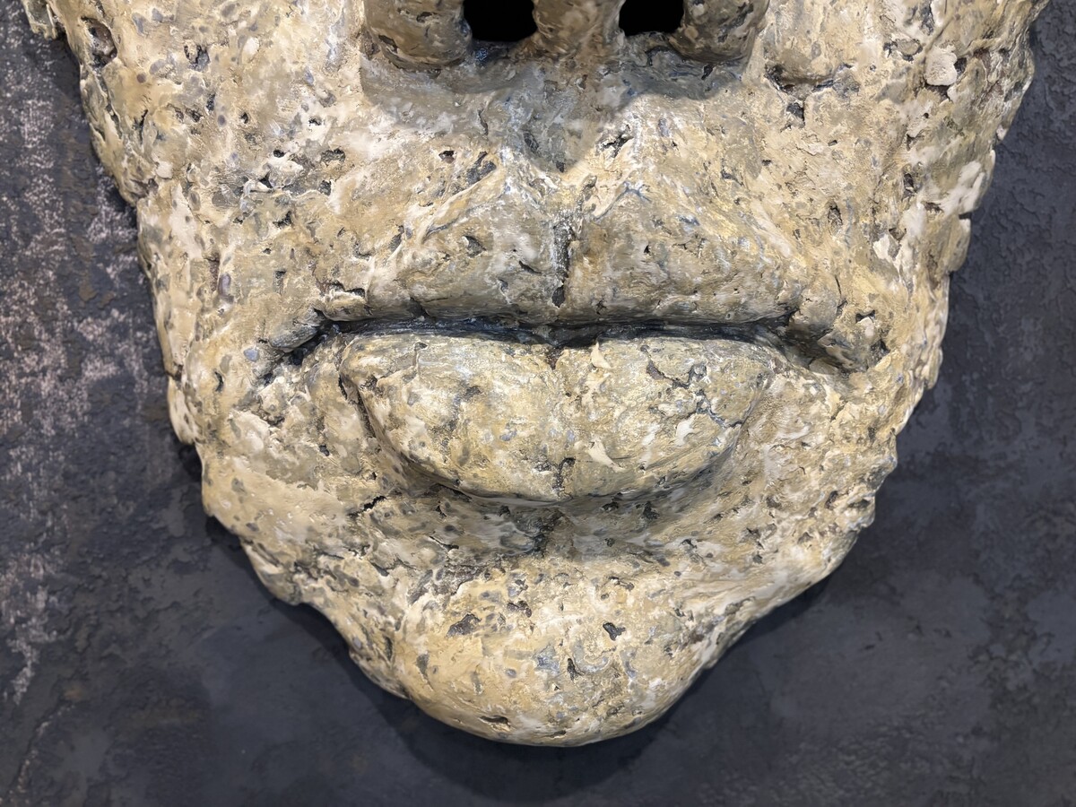 Dekoracyjna maska na ścianę, beżowa płaskorzeźba. Duża płaskorzeźba twarz na czarnej ścianie.