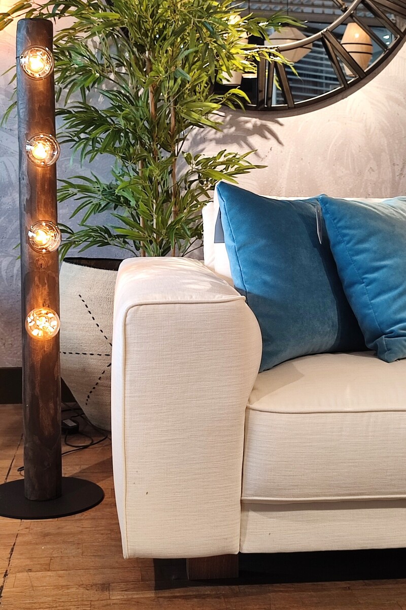 Lampa wielopunktowa, sofa tapicerowana z szerokim podłokietnikiem, poduszki dekoracyjne 45x45