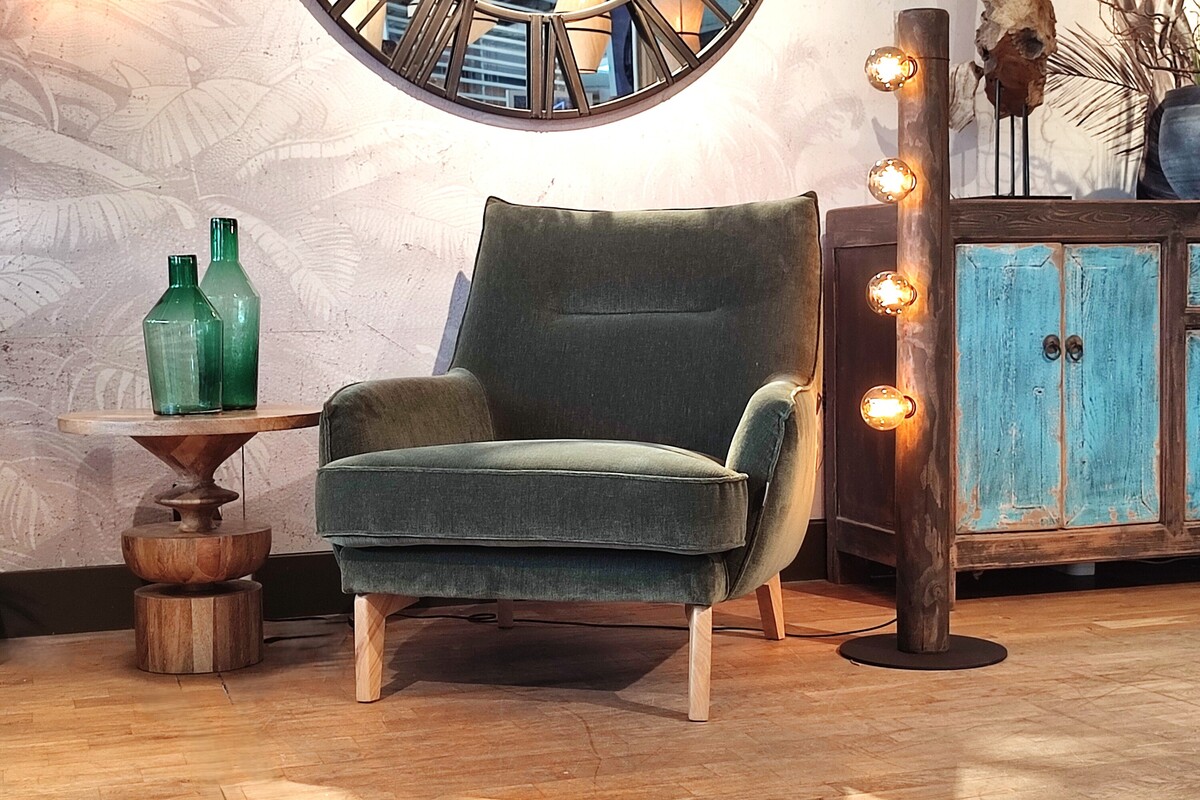 Zielony fotel, salon boho naturalne wnętrze, drewniane dekoracje, lampa industrialna, przytulny salon, styl eklektyczny, komfortowy fotel, inspiracje domowe 