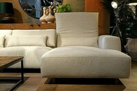 beżowy narożnik modułowy, sofa narożna z regulowanymi zagłówkami, jasna kanapa na tle zielonej tapety, duży zegar na ścianie, ciekawe lampy do salonu, unikatowa komoda z naturalnego drewna (1)