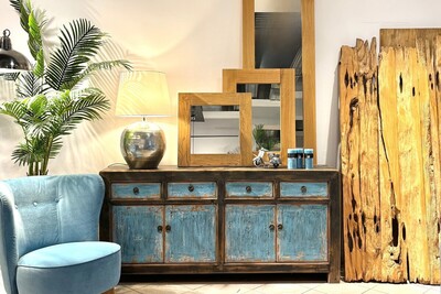 Drewniana komoda błękitna. Aranżacja w stylu boho. Niebieski fotel obrotowy Carmen. Palmy we wnętrzach. Lustra w drewnianych ramach. Drewniane dechy dekoracja